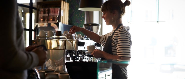 En ung kvinna gör en kaffe på ett café.