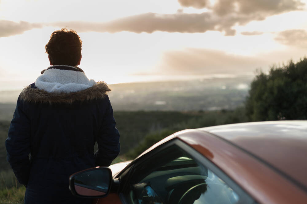 Ungdom står vid bil och ser på utsikt