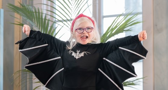 Glad flicka i fladdermusdräkt