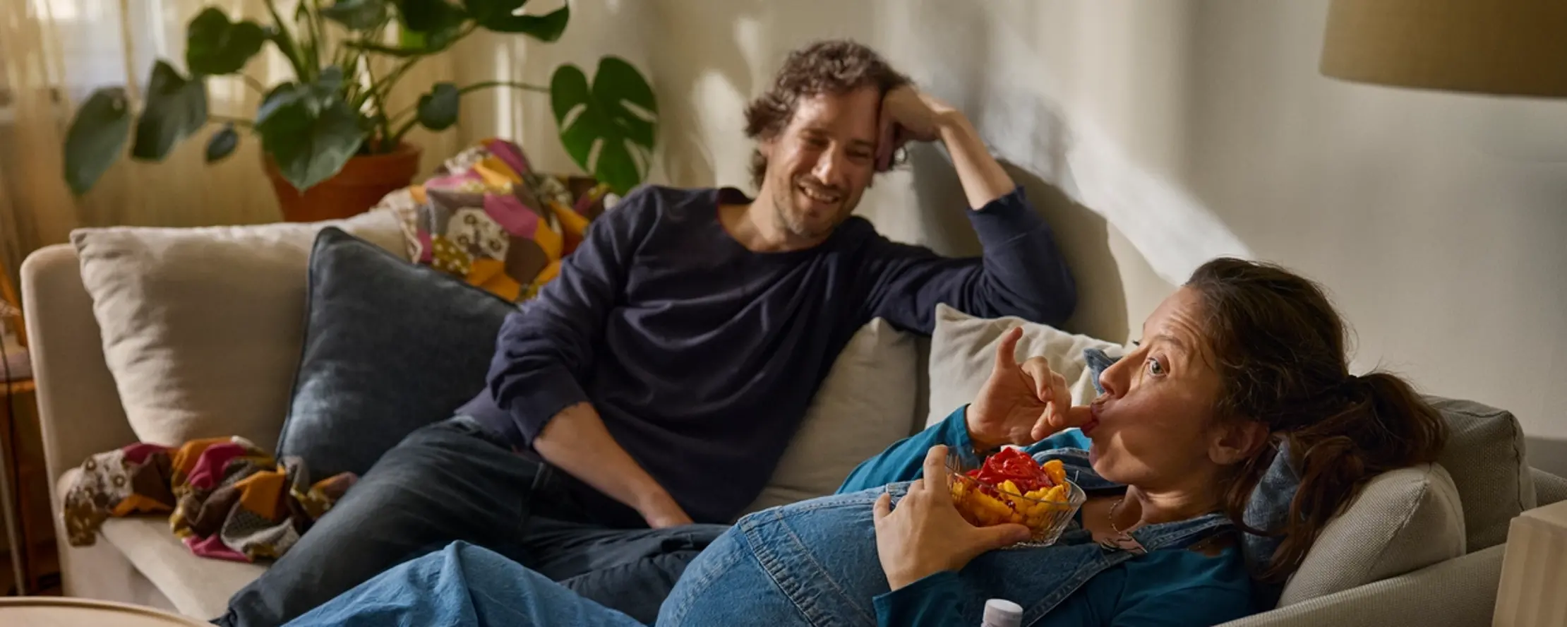 Par som väntar barn sitter i soffa.