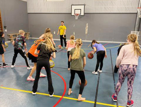 Barn spelar basket.