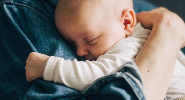 En bebis sover gott mot mammas axel.