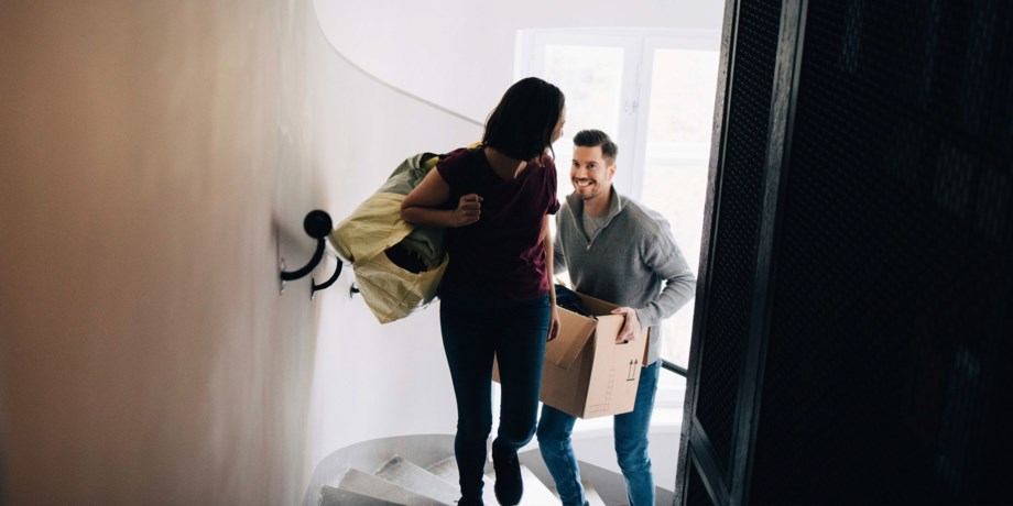 Par bär flyttkartonger i trapphuset