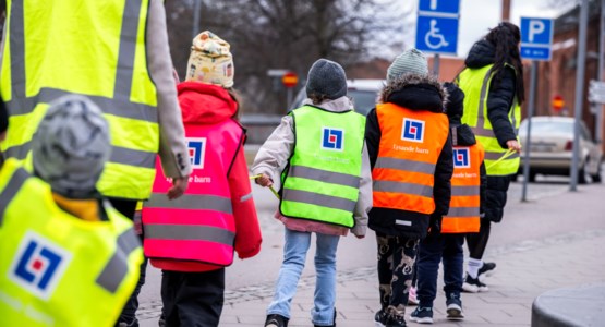 Förskolebarn på promenad med reflexvästar på.