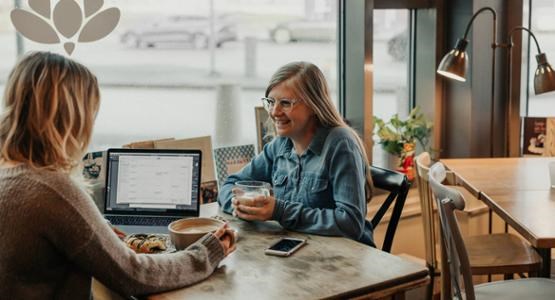 Två tjejer sitter på ett kafé och studerar tillsammans.