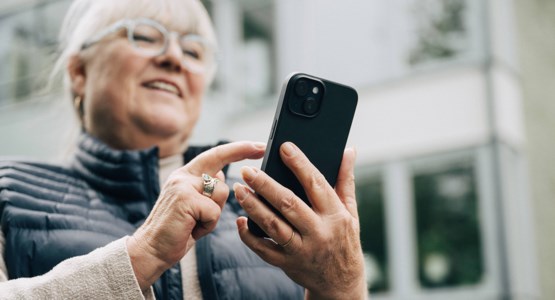 Äldre kvinna tittar på sin mobiltelefon.