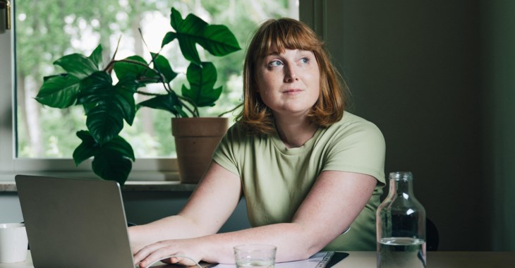 Kvinna vid köksbordet med dator.