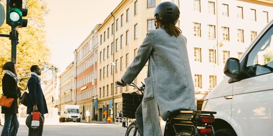 Kvinna på cykel som får grönt vid ett trafikljus.