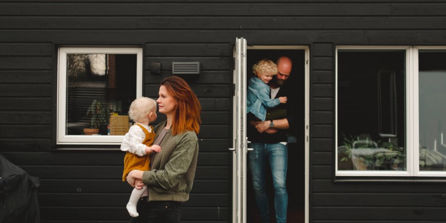 Familj går ut genom ytterdörren på deras svarta villa.