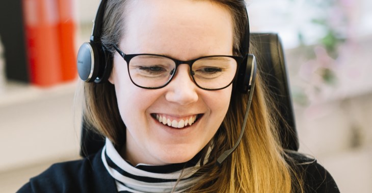 Bild på glad kvinna som sitter i telefon med kund