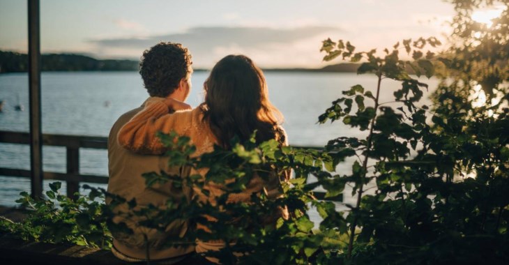 Par sitter på bänk och ser ut över havet.