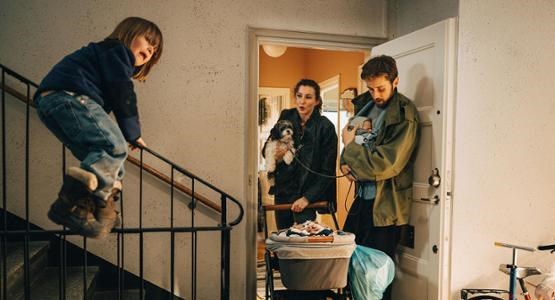 Familj med barnvagn trängs i trapphus.