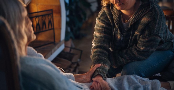 Yngre och äldre kvinna framför brasa.