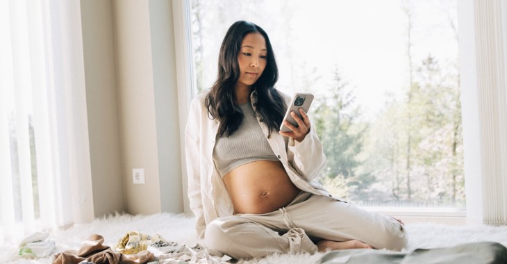 Gravid kvinna kollar i mobilen.