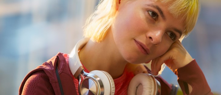 Närbild på en yngre person med hörlurar runt halsen.