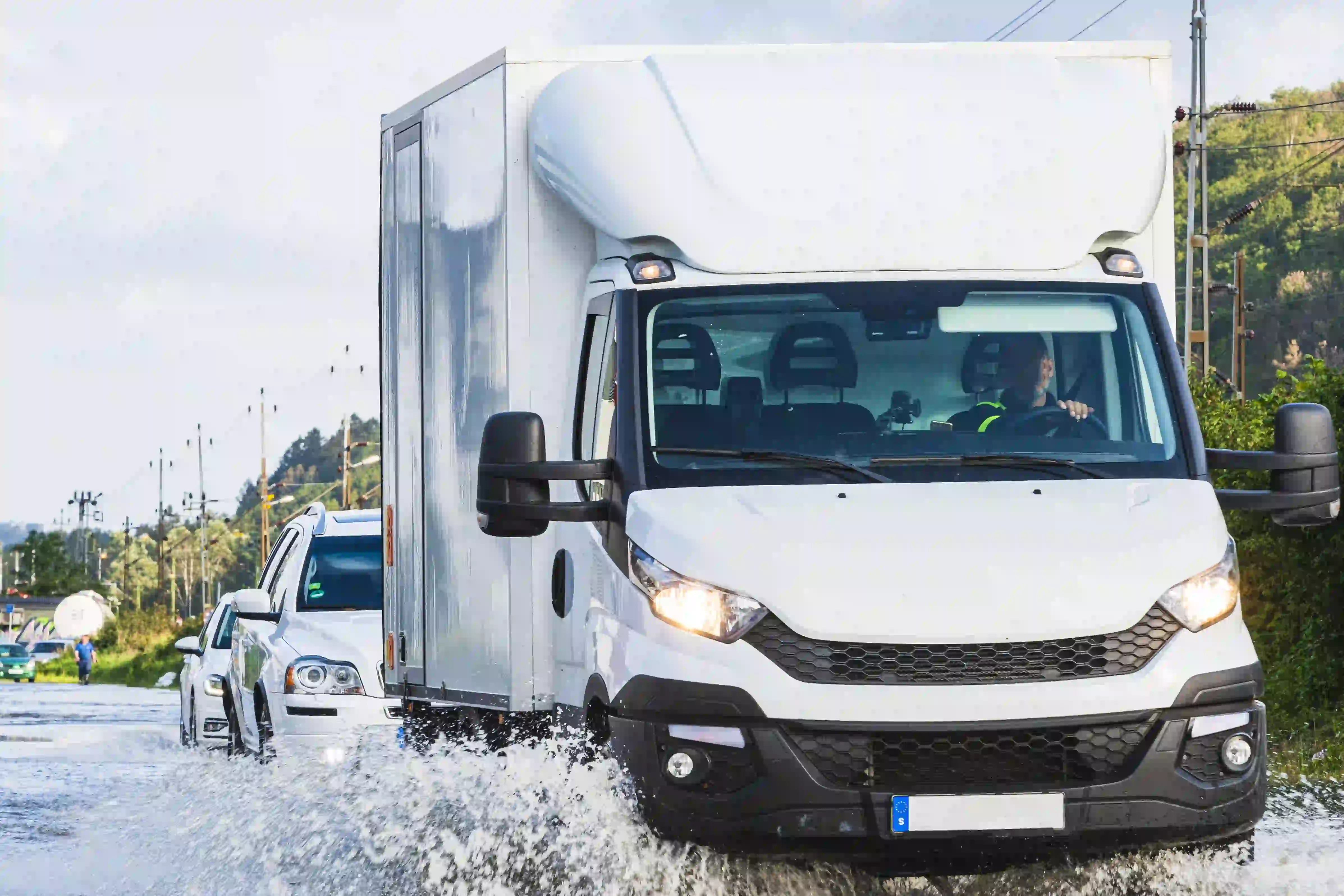 Lastbil kör genom vatten på översvämmad väg, fotografi.