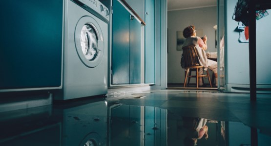 Ett vattenläckage i en tvättstuga med vatten på golvet.