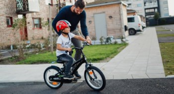 En liten kille lär sig cykla tillsammans med sin pappa.