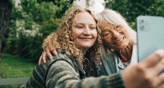 Äldre kvinna med yngre kvinna tar en selfie