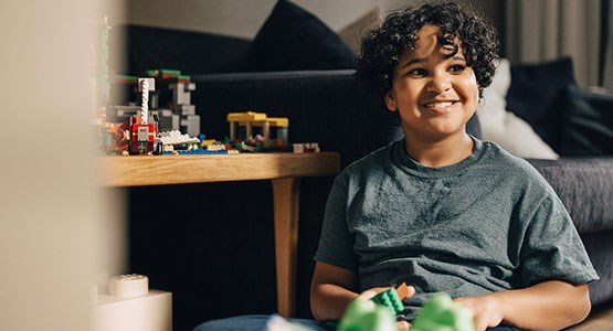 Lockigt barn leker med lego.