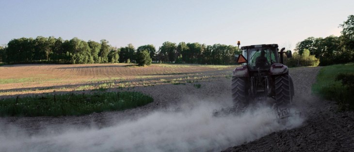 Traktor körs på åker.