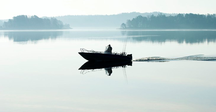 Man kör motorbåt i skärgården, foto.