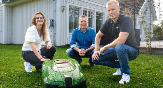Tre personer vid en robogräsklippare.