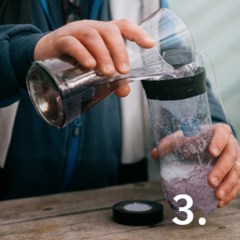 Händer som häller saft i en plastflaska.