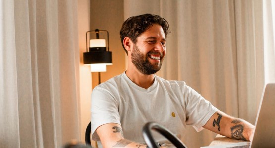 Man jobbar vid köksbord med laptop.