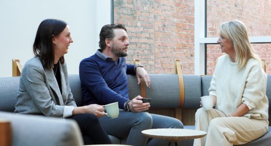 Tre kollegor pratar i en soffa