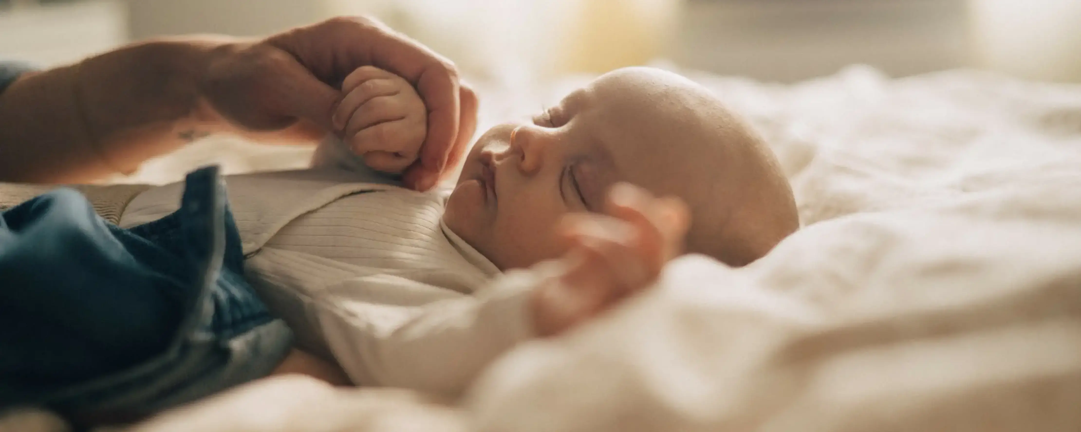 En bebis sover gott på mammas och pappas säng.