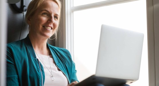 Kvinna med laptop sitter i fönster