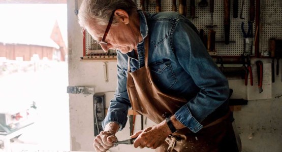 Äldre man som skrapar bort färg från fönster