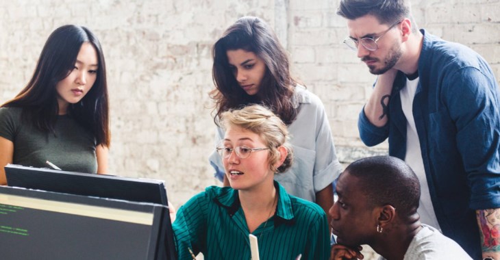 Grupp med människor vid en dator och  i en kontorsmiljö