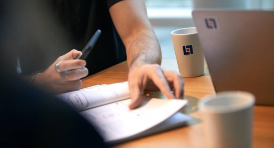 Händer som håller i penna och papper.