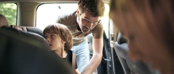 Pappa spänner fast barn i baksätet, foto.