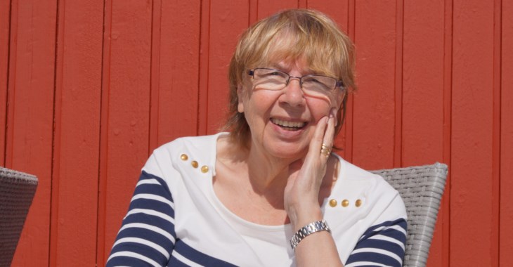 Äldre kvinna sitter på en stol i solen