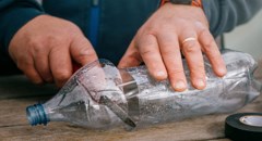 Toppen på en platsflaska skärs av  med kniv