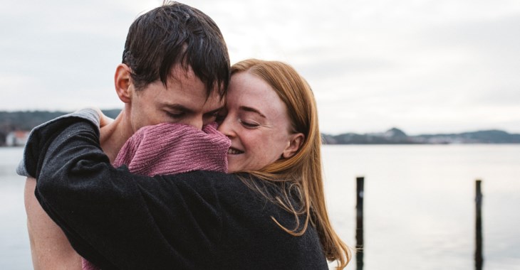 Ung par kramas vid brygga efter bad.