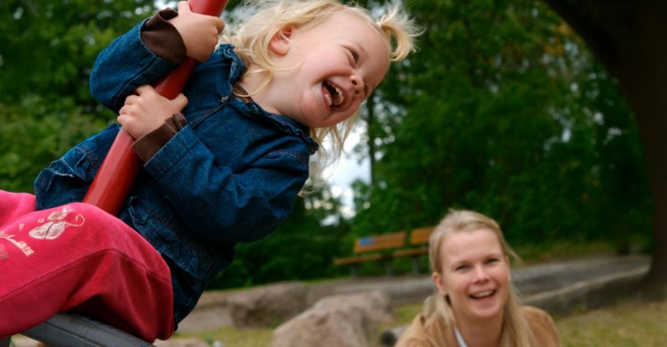 En mamma som ger fart till en liten flicka som glädjs åt den höga farten.