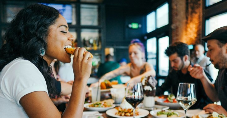 Människor sitter i ett sällskap och äter på restaurang.