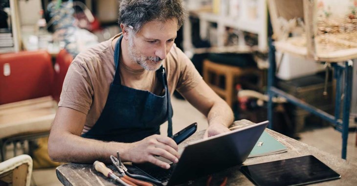 Foto på en man i en verkstad som sitter vid en dator.