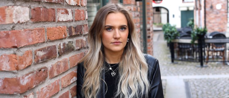 Ung kvinna i stadsmiljö. Tittar in i kameran.