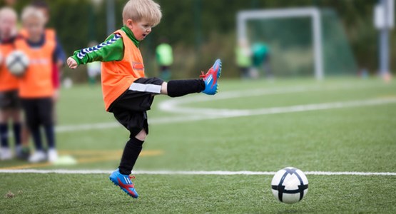 Liten kille spelar fotboll.