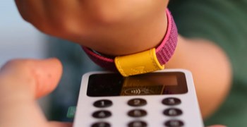 Ett barn blippar sitt betalarmband för att betala