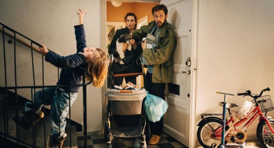 Familj med två barn, hund och barnvagn i trapphus.