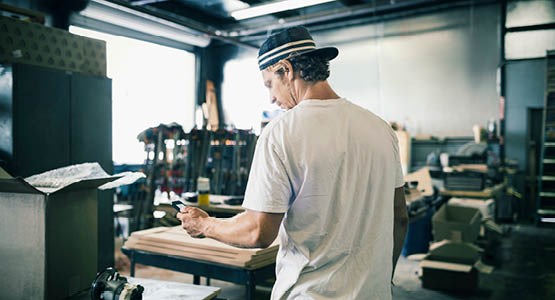 Arbetande man som kollar ner i telefonen. 