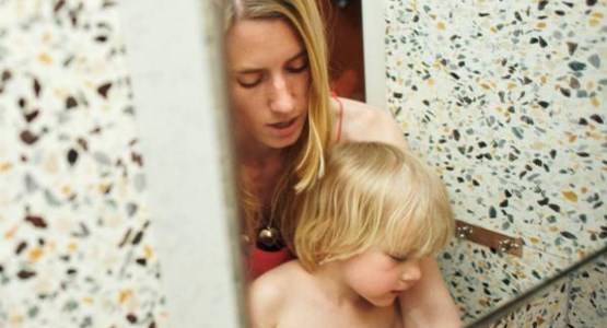 En mamma och en son syns i en badrumsspegel.