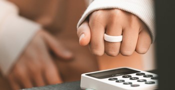 En kvinna blippar sin betalring när hon handlar.