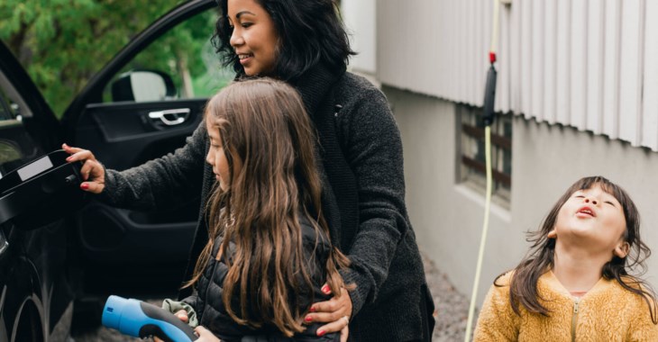 Mamma med barn som laddar elbilen.